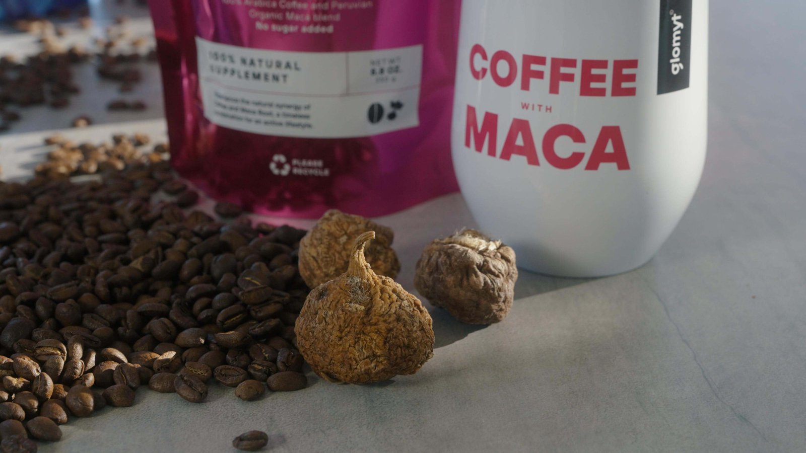 Dried maca roots beside coffee beans and Glomyt Pink